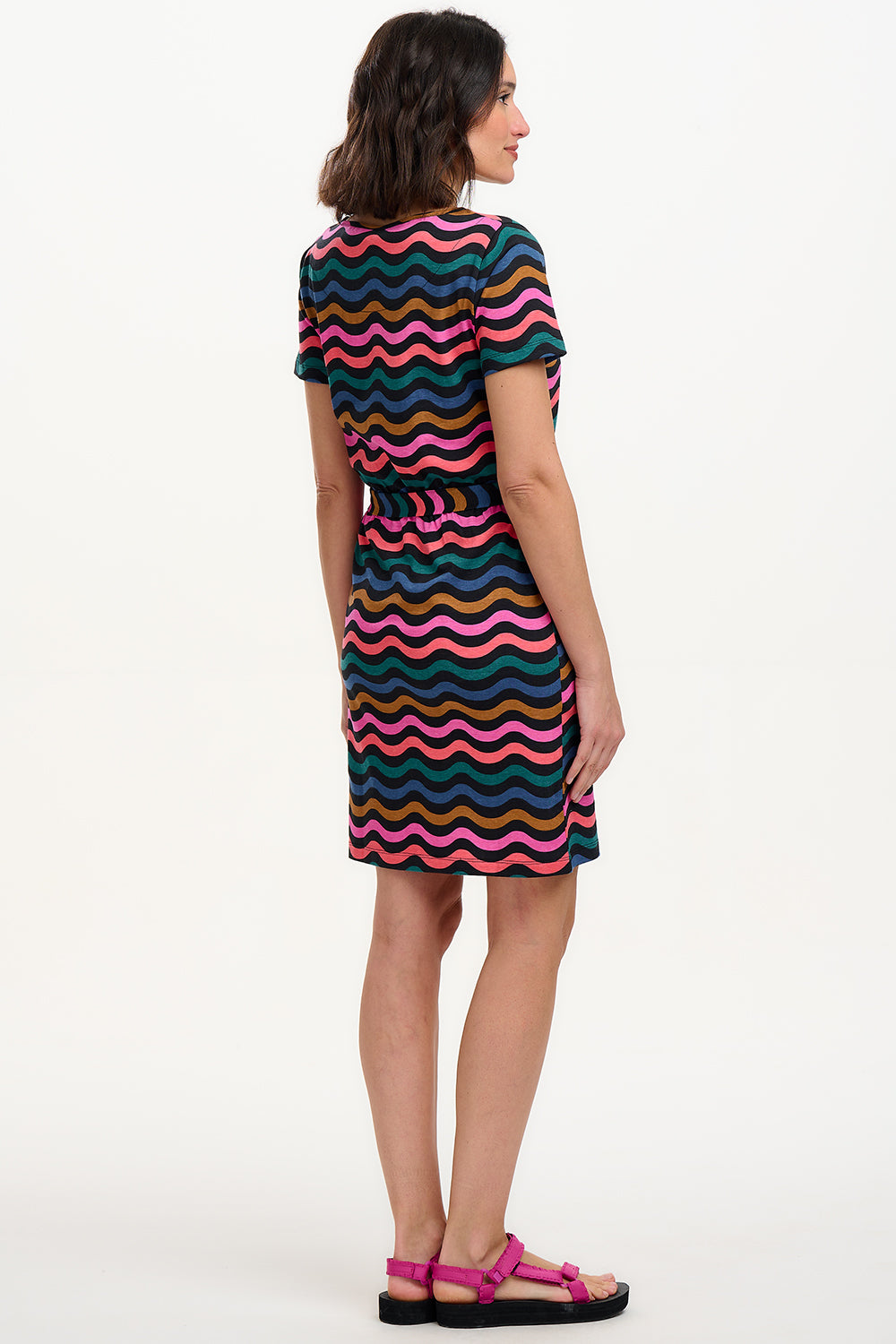 A model wearing a short-sleeved mini dress with a wavy chevron stripe pattern in black, teal, navy, tan, pink, and coral colors.