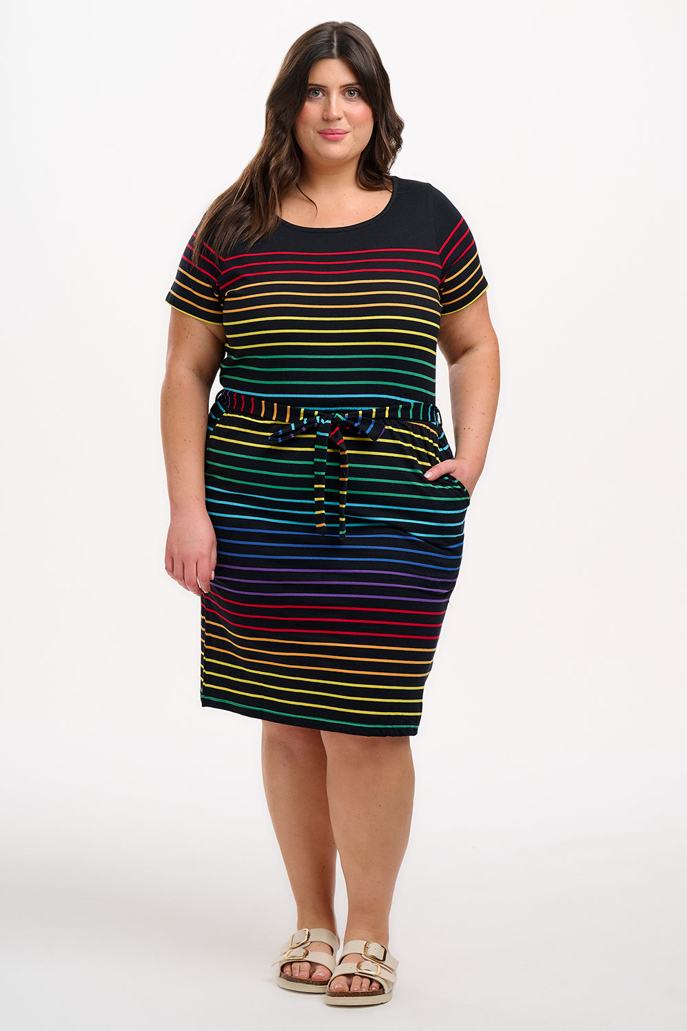 A model wearing a short-sleeved black mini dress with a colorful striped pattern and pockets
