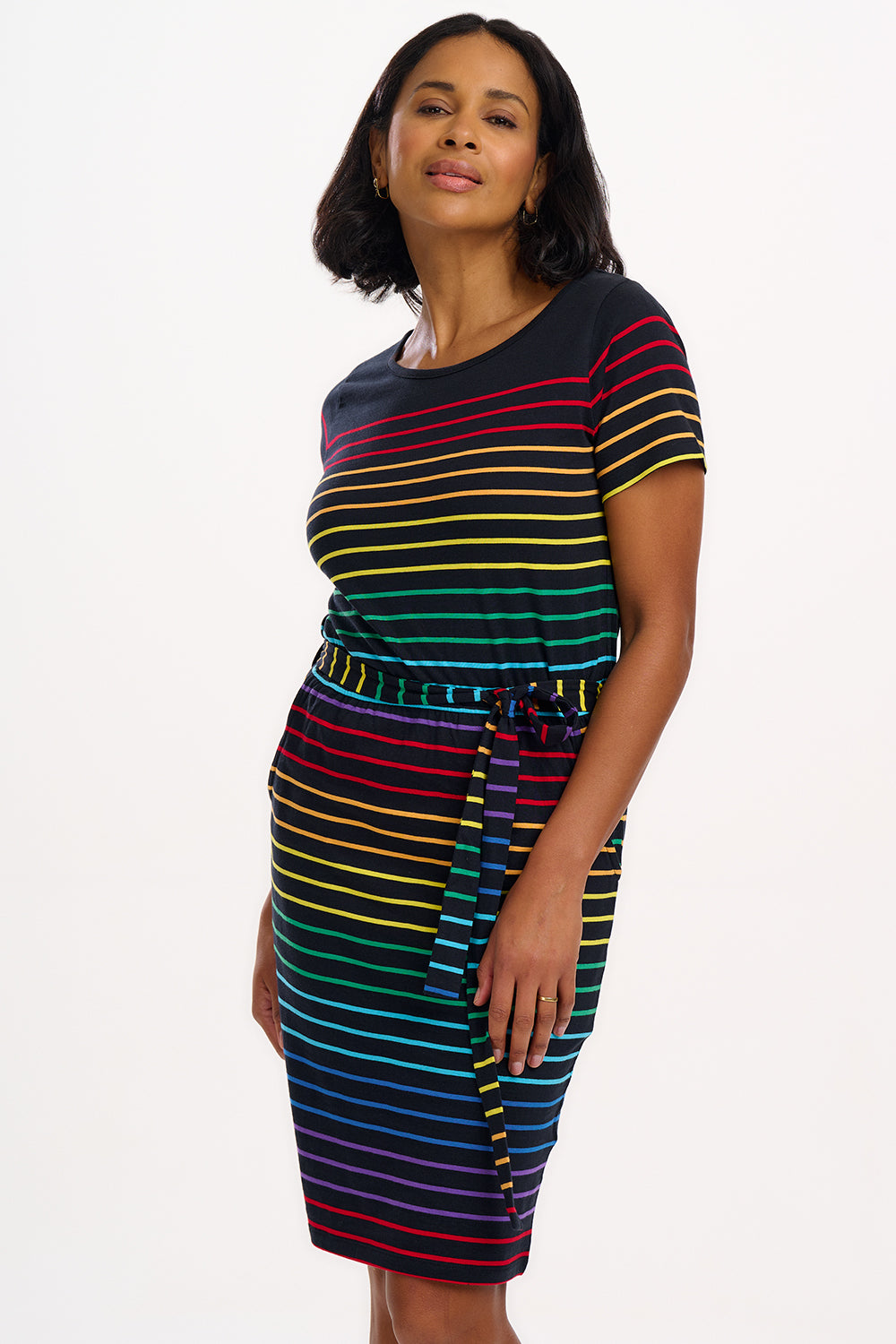 A model wearing a short-sleeved black mini dress with a colorful striped pattern and pockets