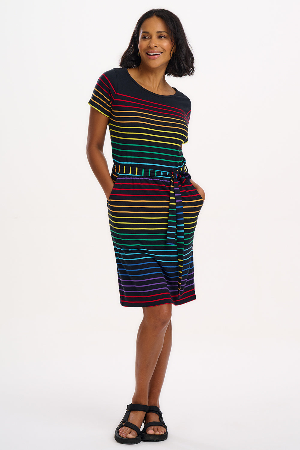 A model wearing a short-sleeved black mini dress with a colorful striped pattern and pockets