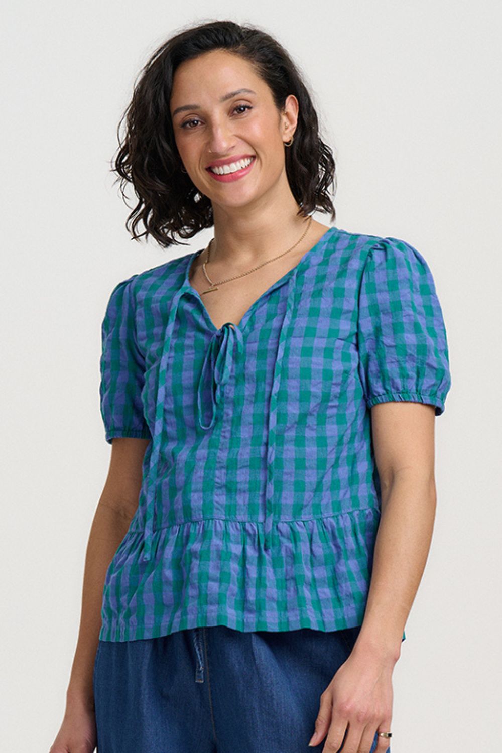 Woman wearing a blue and green checkered blouse against a white background