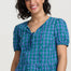 Woman wearing a blue checkered top and denim shorts on a white background