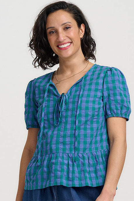 Woman wearing a blue checkered top and denim shorts on a white background
