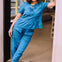 Woman in a blue outfit standing in a doorway.