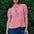 Woman wearing a pink and white striped top with blue shorts against a green leafy background