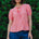 Woman wearing a pink and white striped top with blue shorts against a green leafy background
