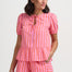 Woman wearing a pink and white striped outfit on a plain background