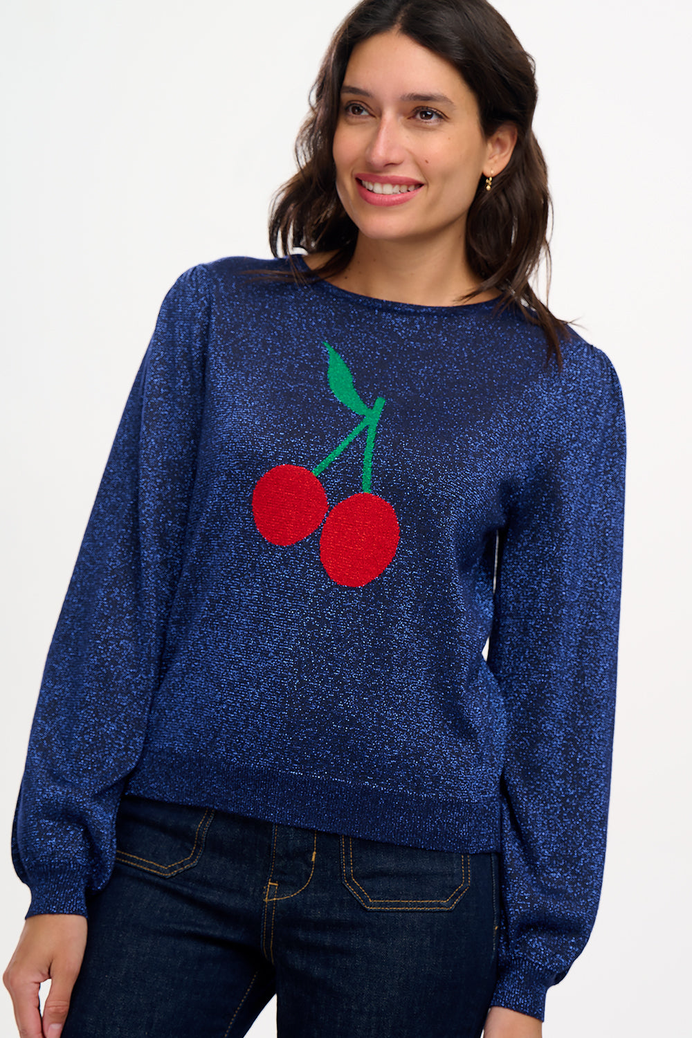 A woman wearing a navy blue jumper with a large red and green cherry motif on the front.