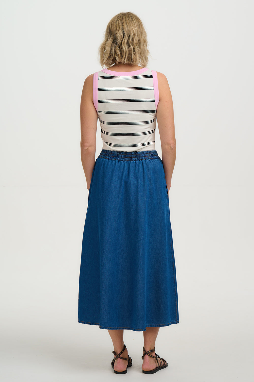 Woman wearing a striped tank top and blue skirt on a white background