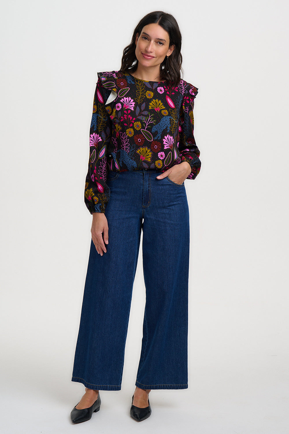Woman wearing a colorful floral blouse and blue jeans on a white background