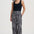 Woman wearing black tank top and geometric patterned pants on a white background