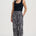 Woman wearing black tank top and geometric patterned pants on a white background