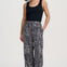 Woman wearing black tank top and geometric patterned pants on a white background
