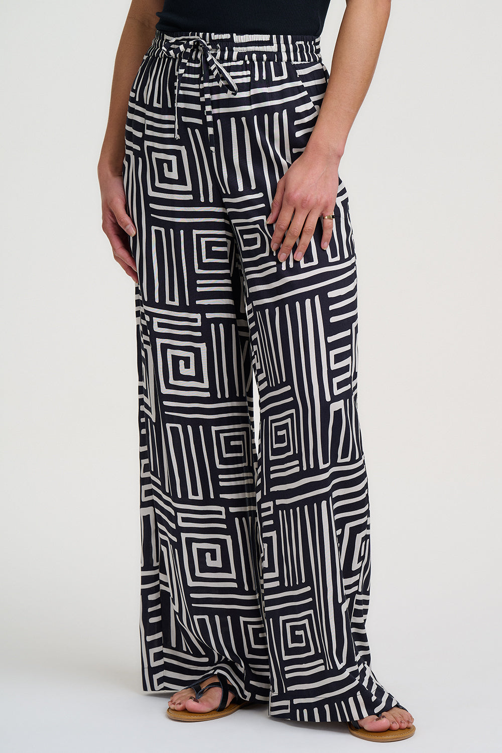 Black and white geometric patterned pants worn by a person on a white background