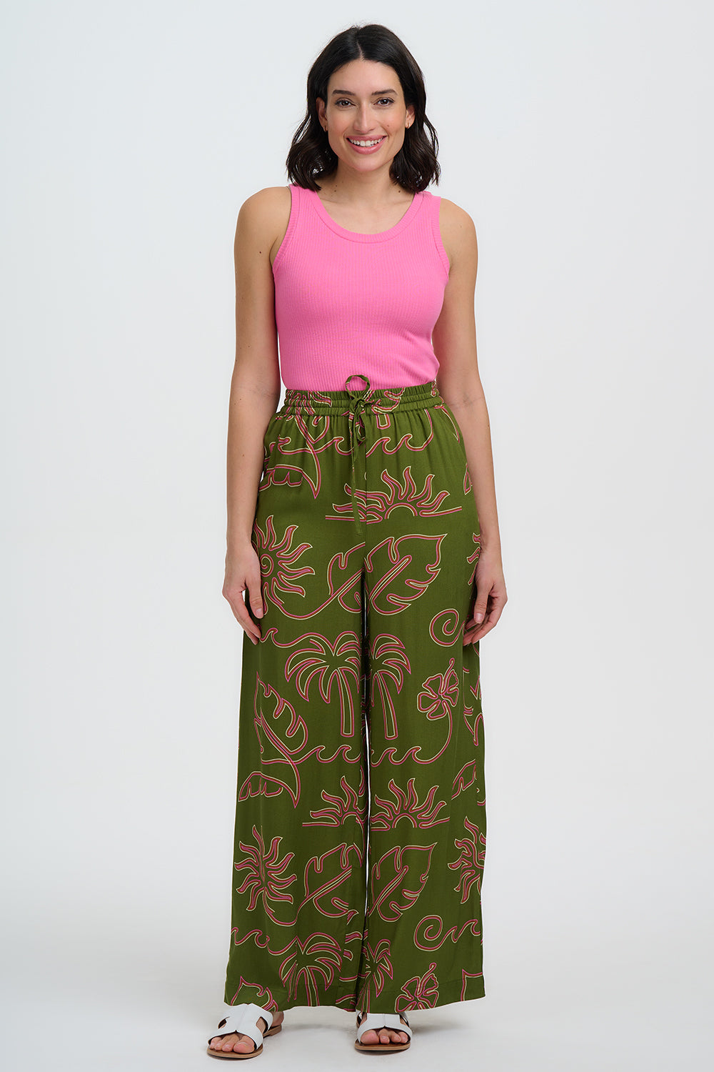 Woman wearing a pink top and green patterned pants on a white background