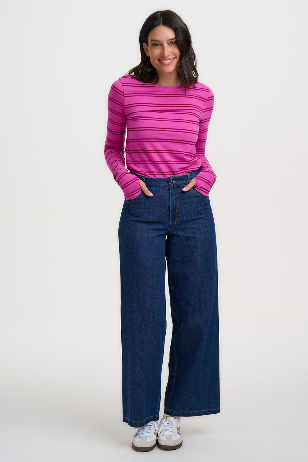 Woman wearing a pink striped shirt and blue jeans on a white background
