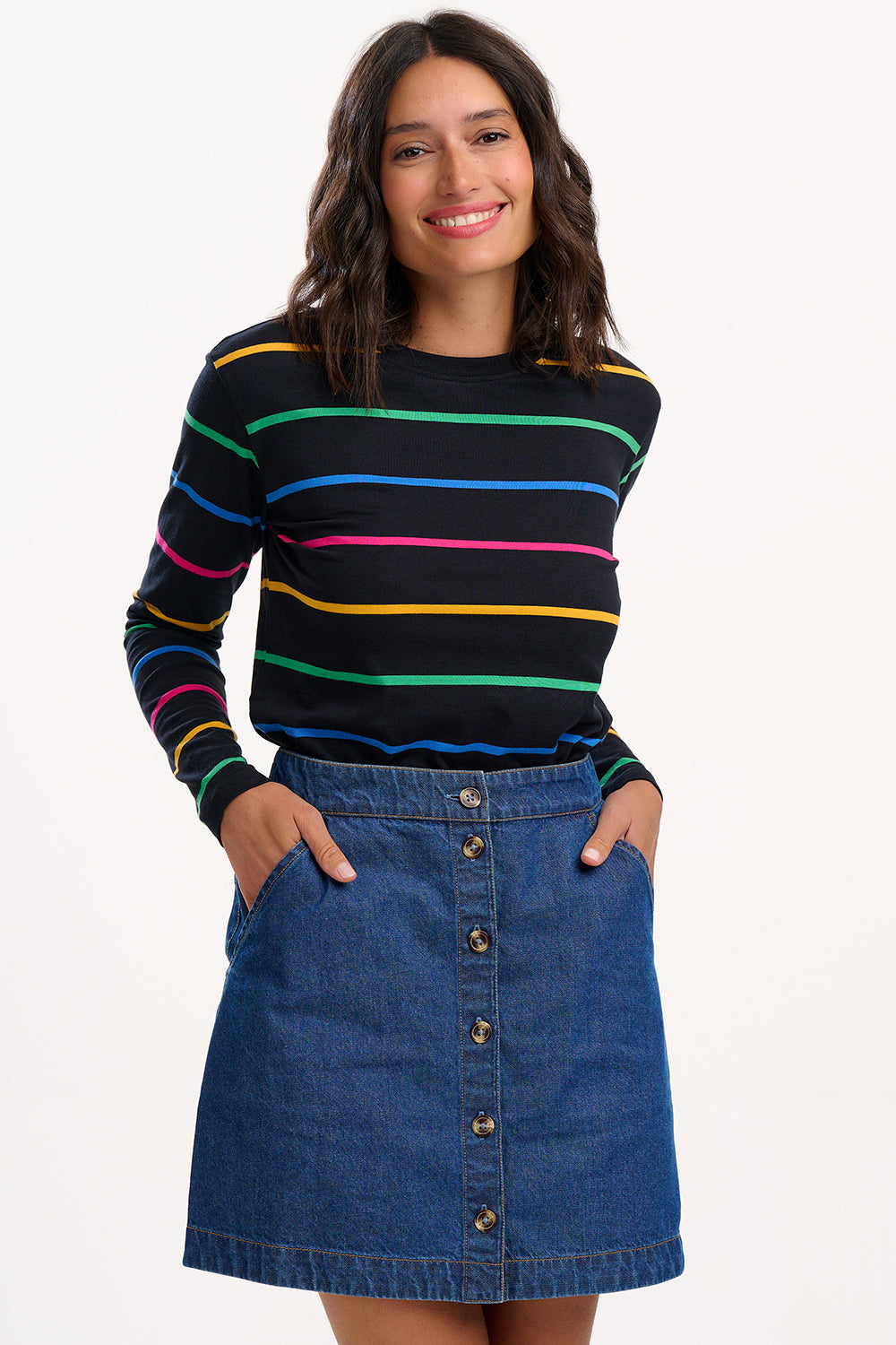 Suagrhill Brighton model wearing a black sweater with colorful stripes and a blue denim skirt on a white background