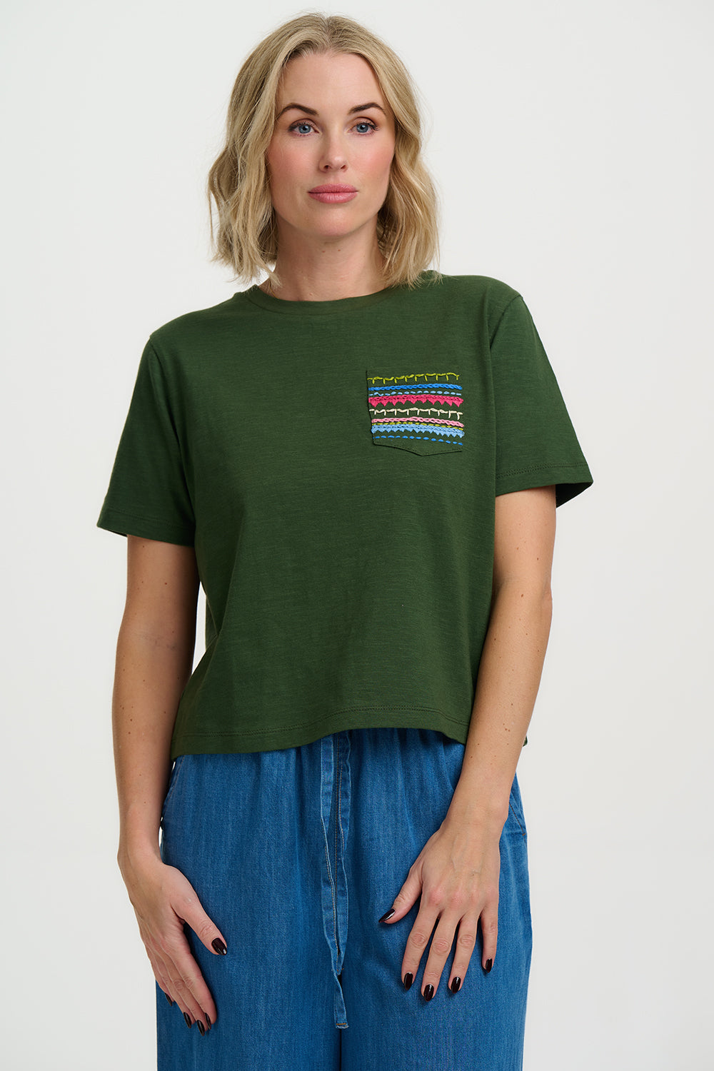 Woman wearing a green t-shirt with a colorful pocket design on a white background