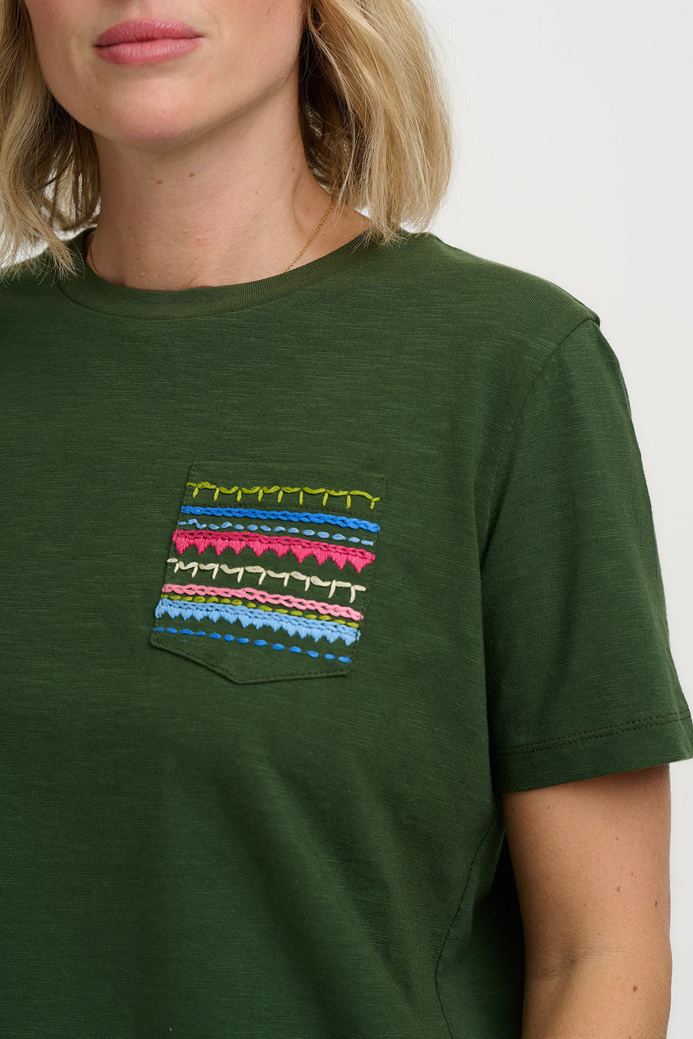 Green t-shirt with colorful pocket design worn by a person on a white background
