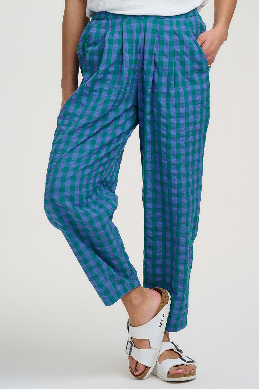 Person wearing blue and green checkered pants on a white background