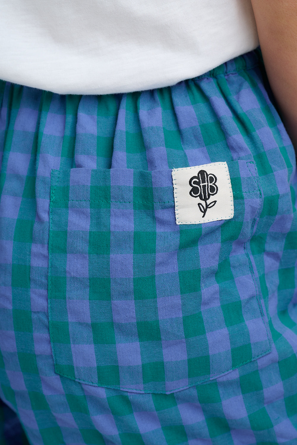 Green and purple checkered shorts with a brand logo on the pocket.