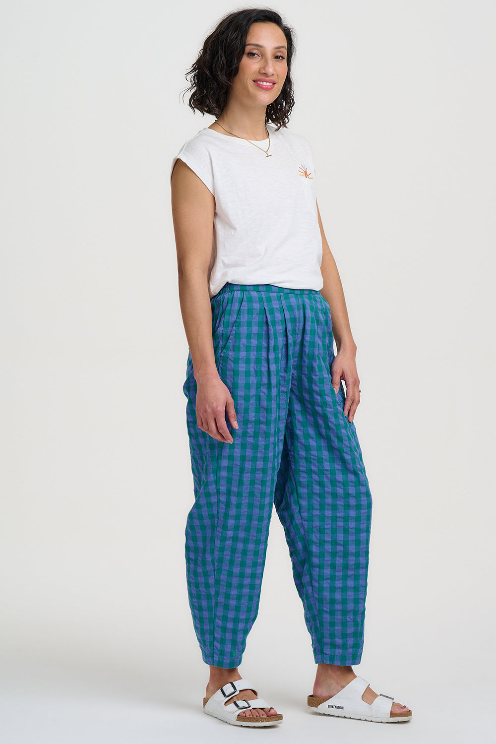 Woman wearing a white top and blue checkered pants on a white background