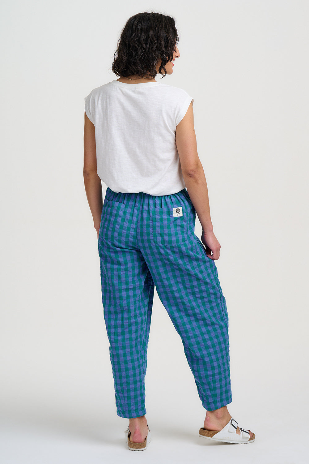 Person wearing blue checkered pants and a white top on a white background