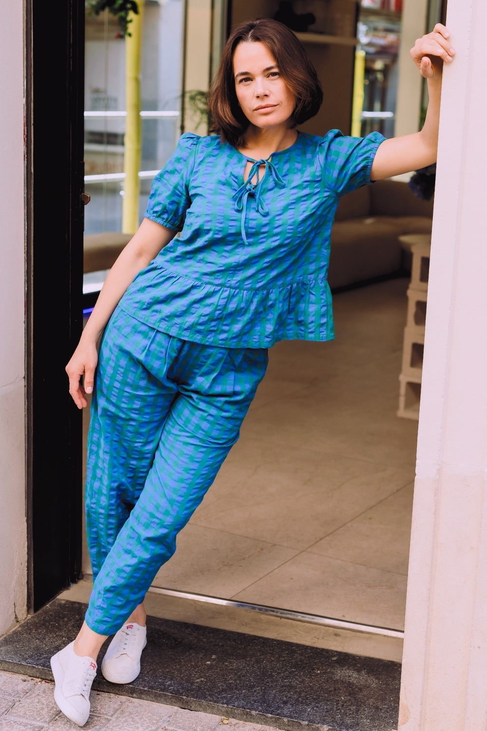 Woman in a blue outfit standing in a doorway.
