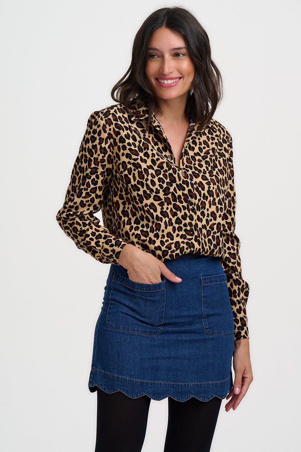 Woman wearing a leopard print blouse and denim skirt on a white background