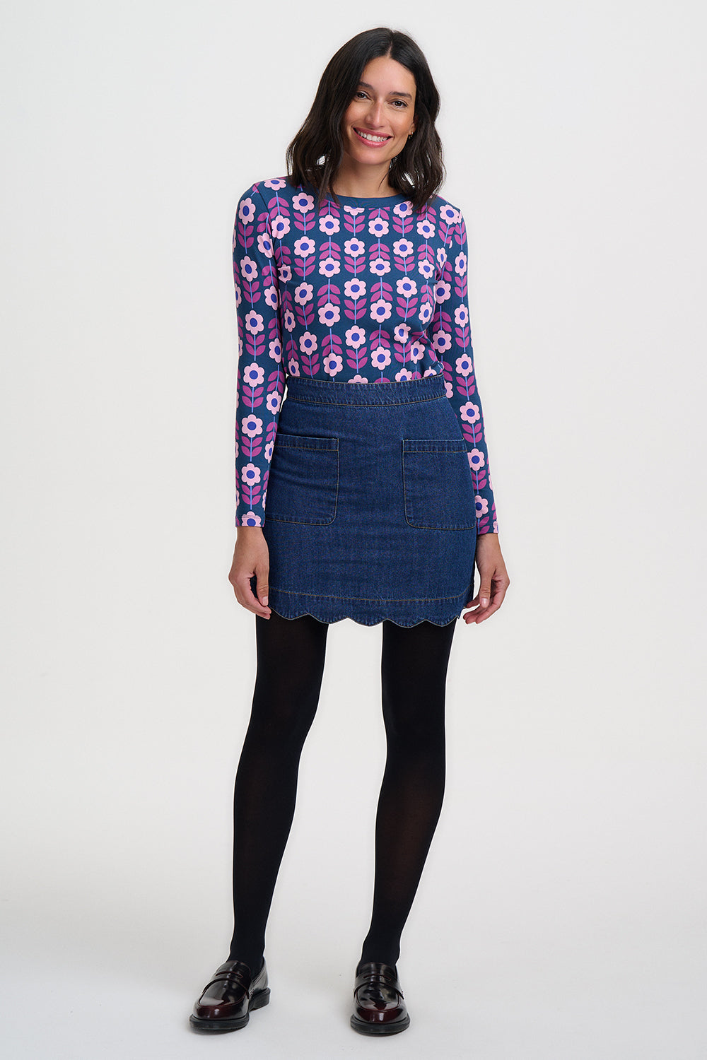 Woman wearing a floral patterned shirt and denim skirt on a white background