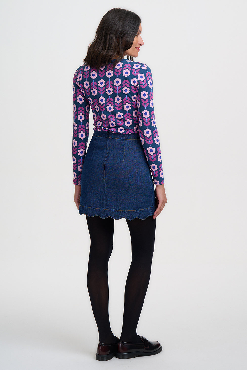 Woman wearing a floral blouse and denim skirt on a white background