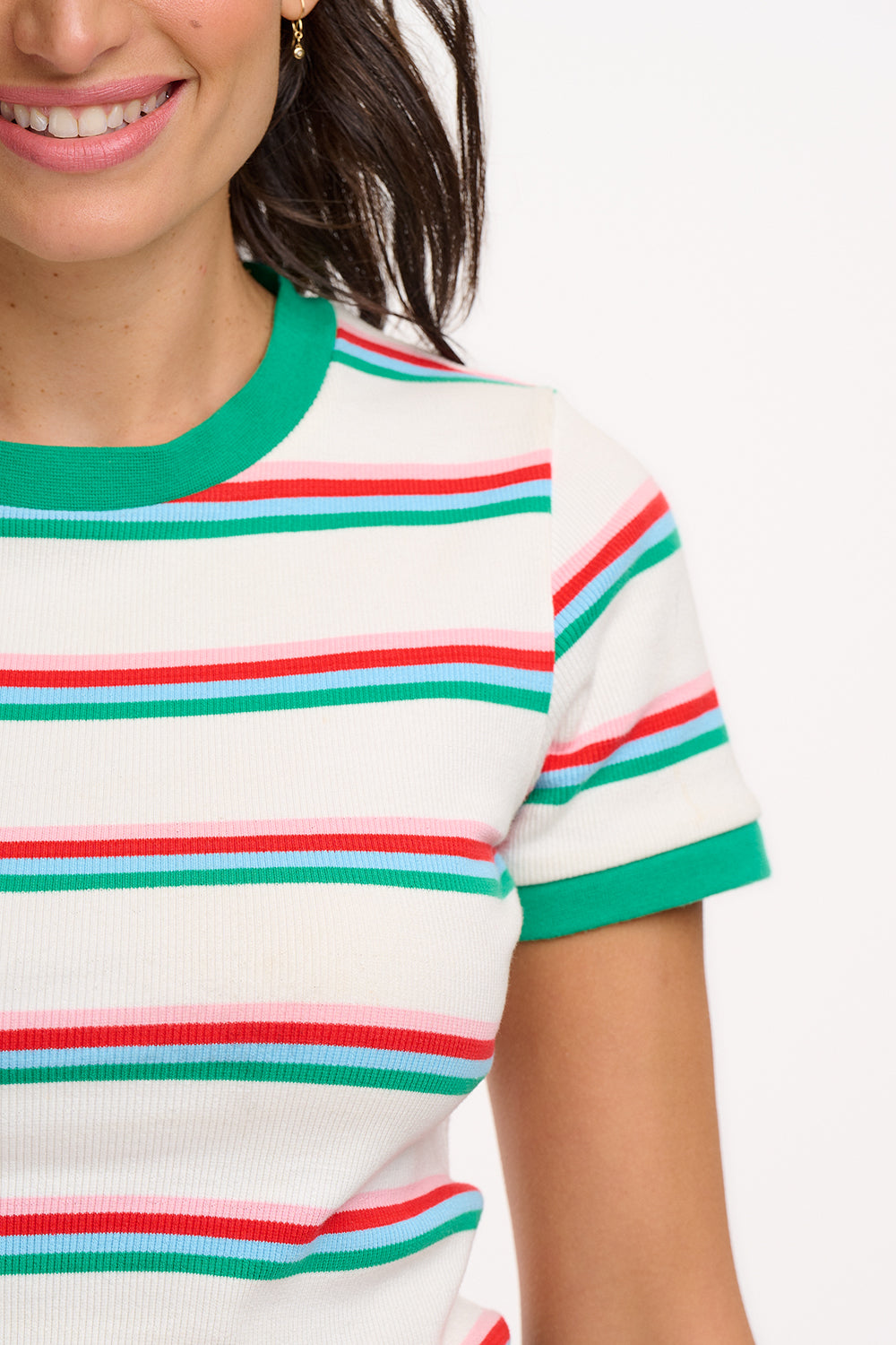 A woman wearing an off-white fitted t-shirt with retro stripes in red and green colors, and contrast cuffs.