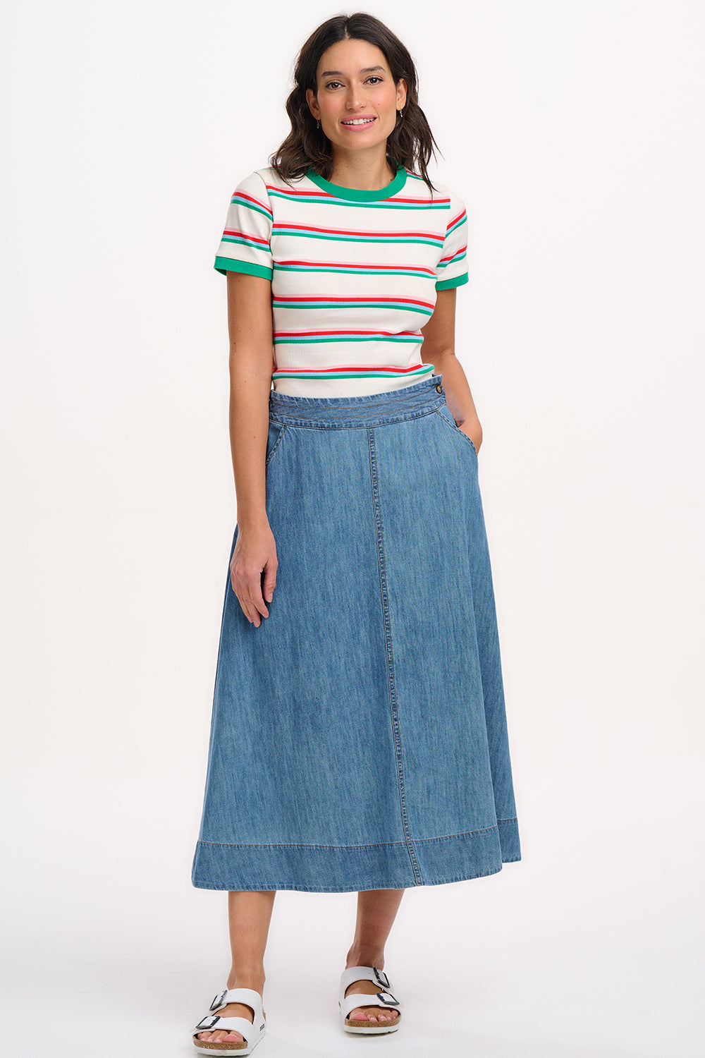 A woman wearing an off-white fitted t-shirt with retro stripes in red and green colors, and contrast cuffs.