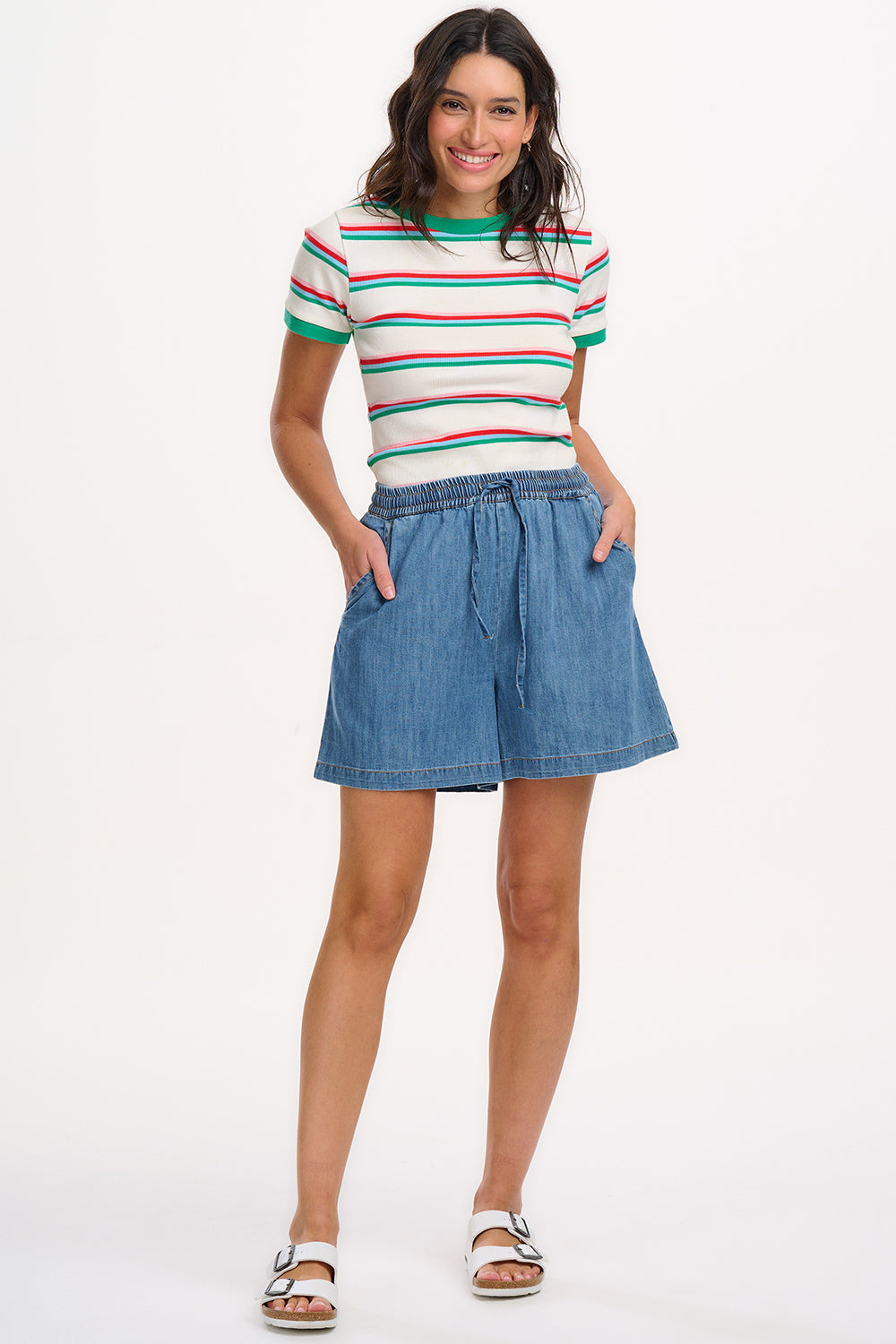 A woman wearing an off-white fitted t-shirt with retro stripes in red and green colors, and contrast cuffs.