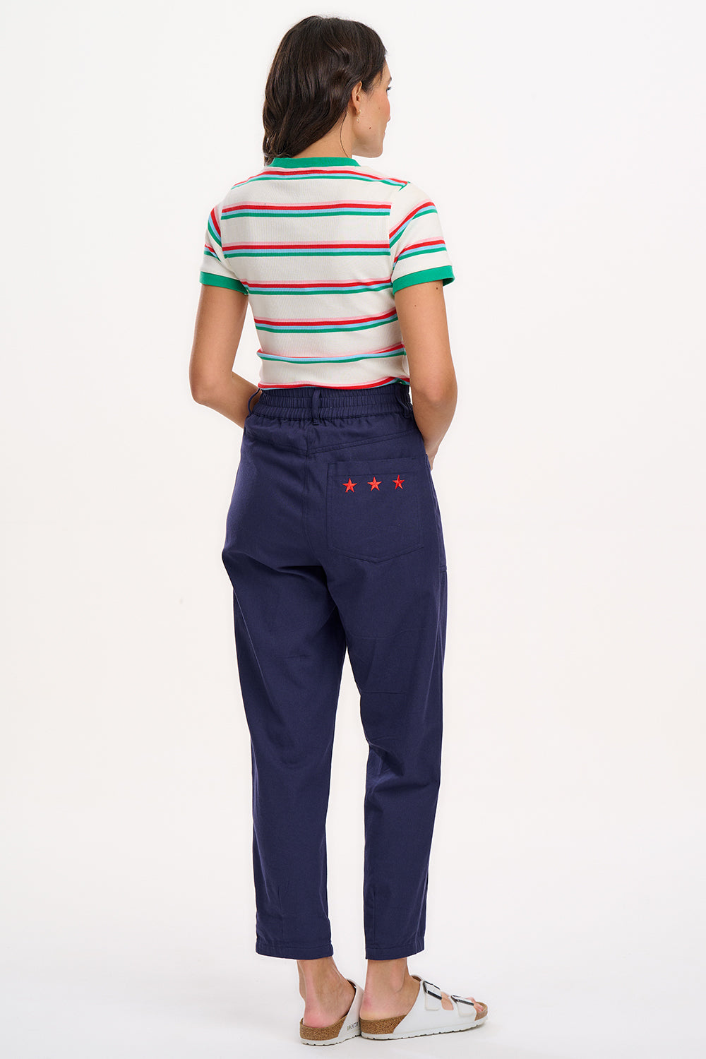 A woman wearing an off-white fitted t-shirt with retro stripes in red and green colors, and contrast cuffs.