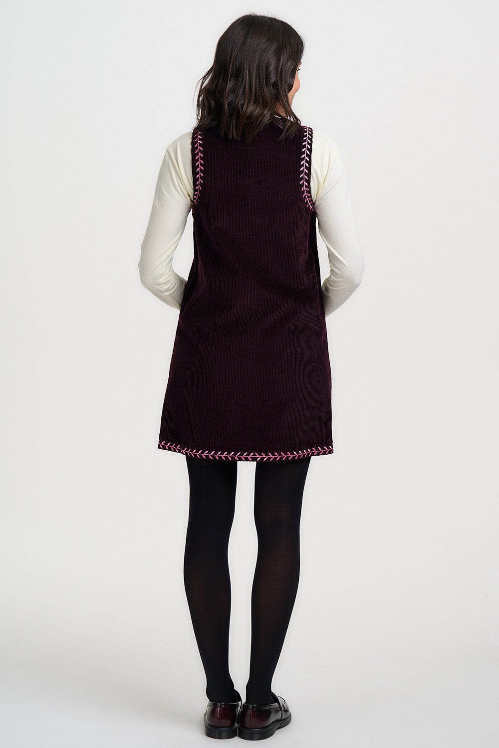Person wearing a dark purple dress with white trim on a white background