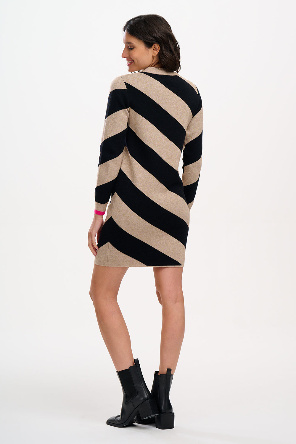 A woman wearing a beige and black diagonal striped knit dress with long sleeves and a crew neck.