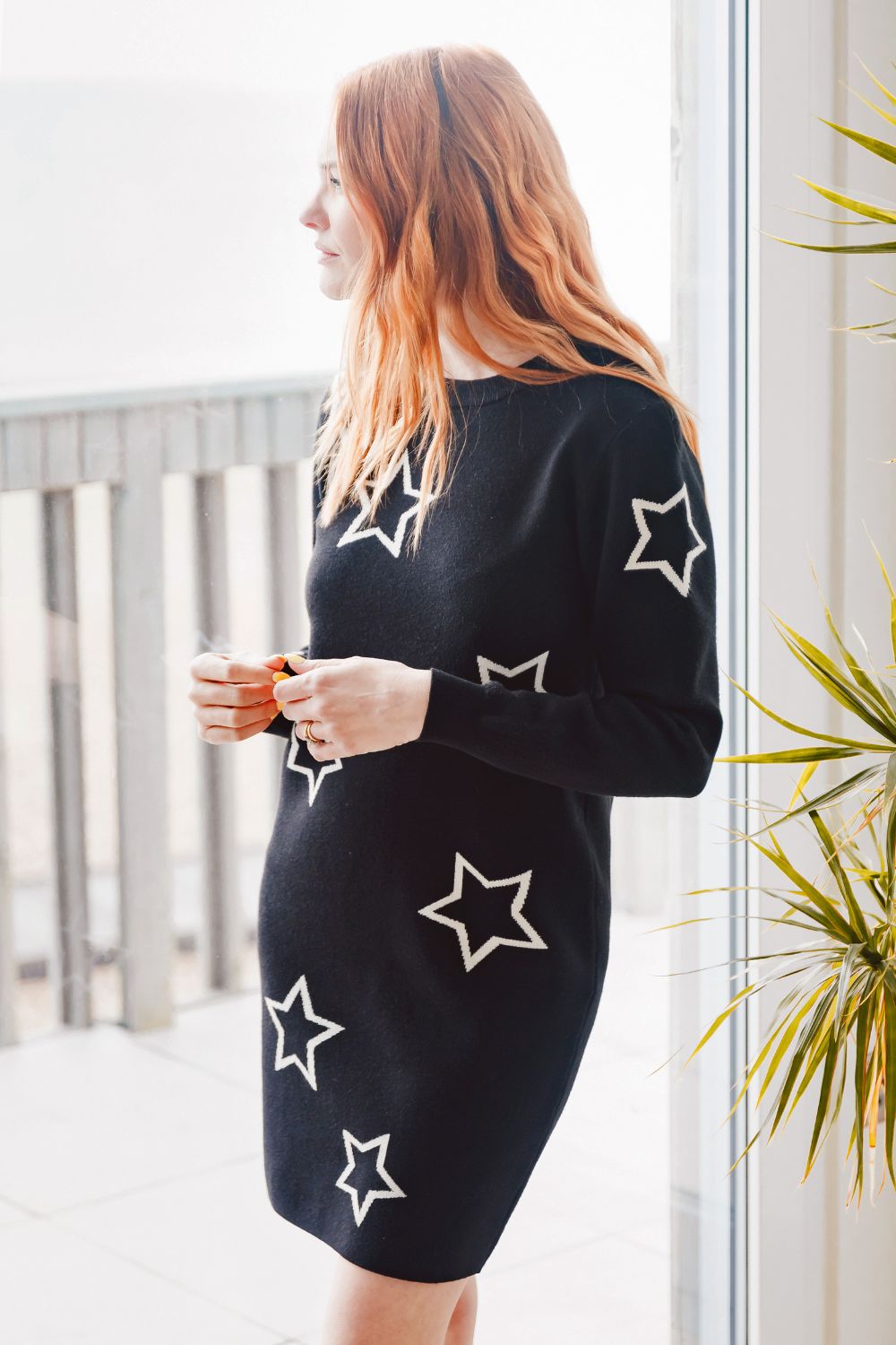 Woman wearing a black dress with star patterns on a balcony