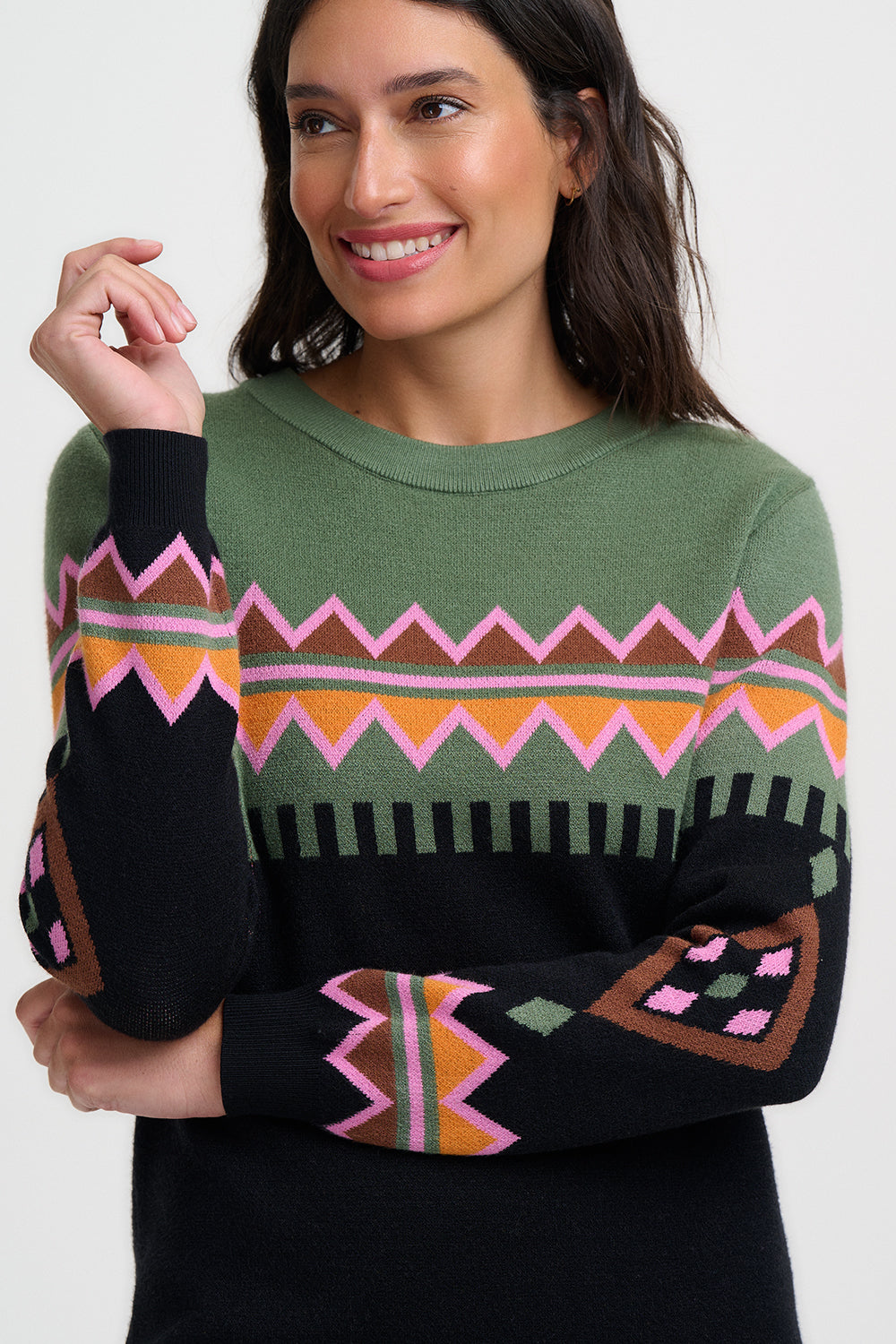 Woman wearing a green sweater with colorful geometric patterns on a white background
