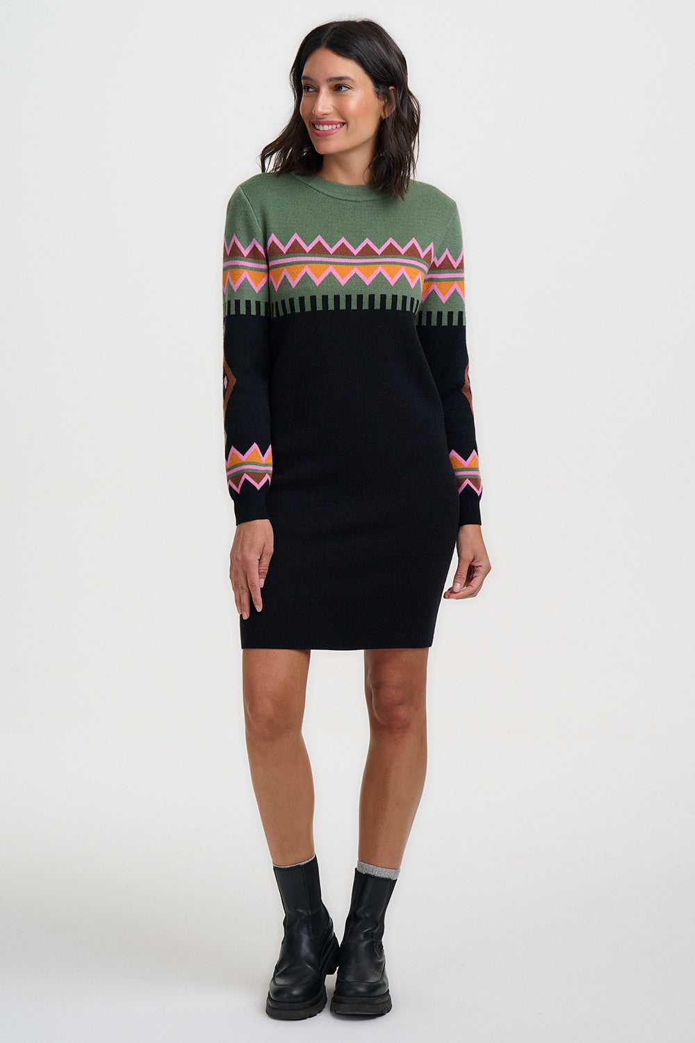 Woman wearing a black sweater dress with a colorful pattern on a white background