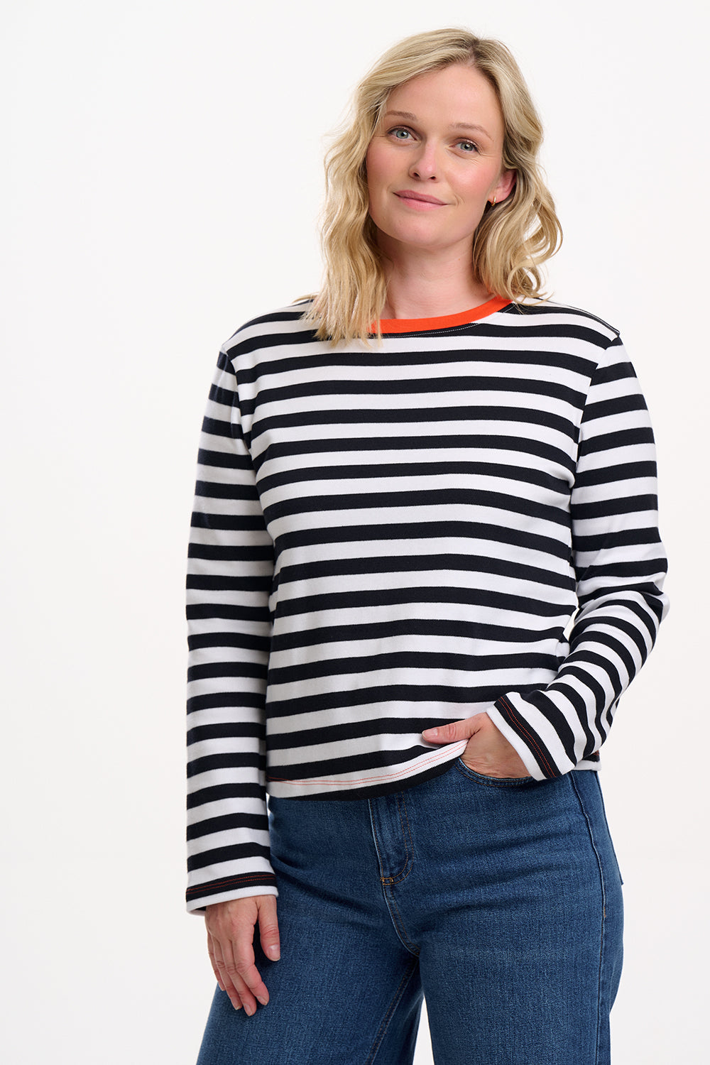 Sugarhill Brighton model wearing a black and white striped sweater with blue jeans on a white background