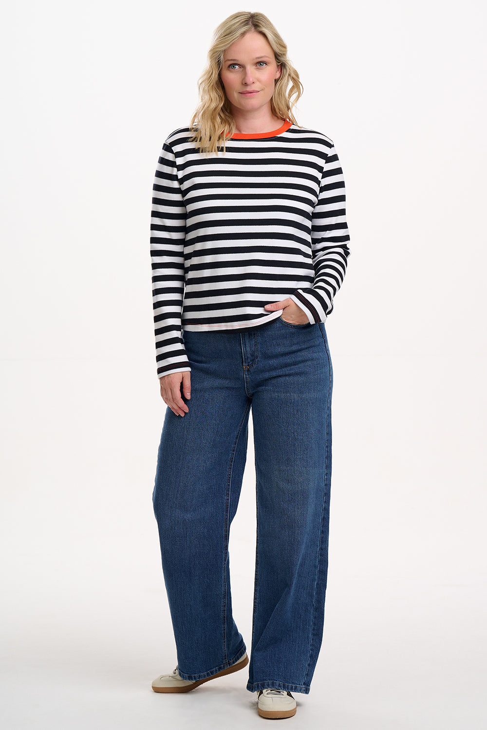 Sugarhill Brighton model wearing a black and white striped sweater and blue jeans on a white background