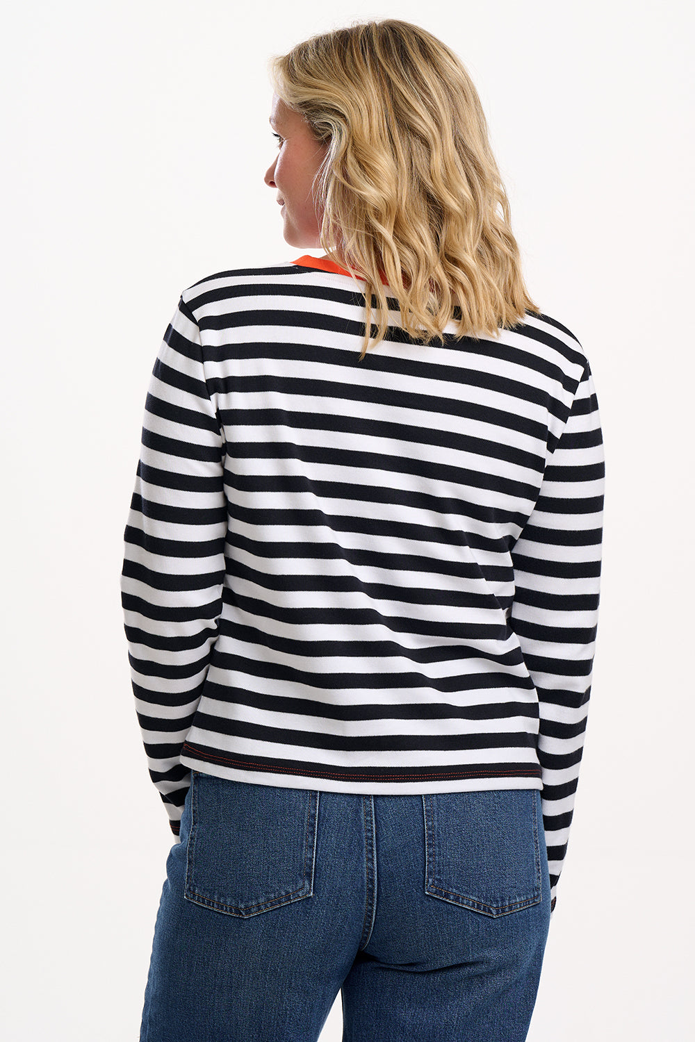 Sugarhill Brighton model wearing a black and white striped shirt and blue jeans on a white background