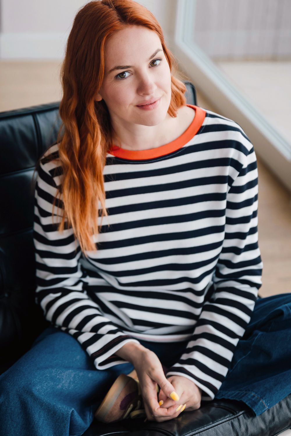 Woman wearing a striped sweater sitting on a couch.