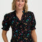 Woman wearing a black floral blouse with colorful flowers on a white background