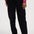 A person wearing loose black pants with a pink ribbed sweater and white sneakers, shown from the chest down against a plain light background.
