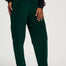 A person wearing dark green corduroy jogger pants with an elastic waistband, styled with a black sweatshirt and white sneakers with gold stripes, shown from the waist down on a light gray studio background.