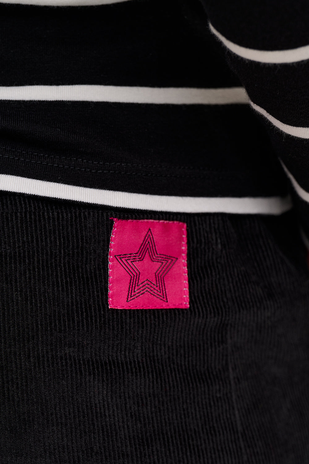 Close-up of a black and white striped garment with a pink star label.