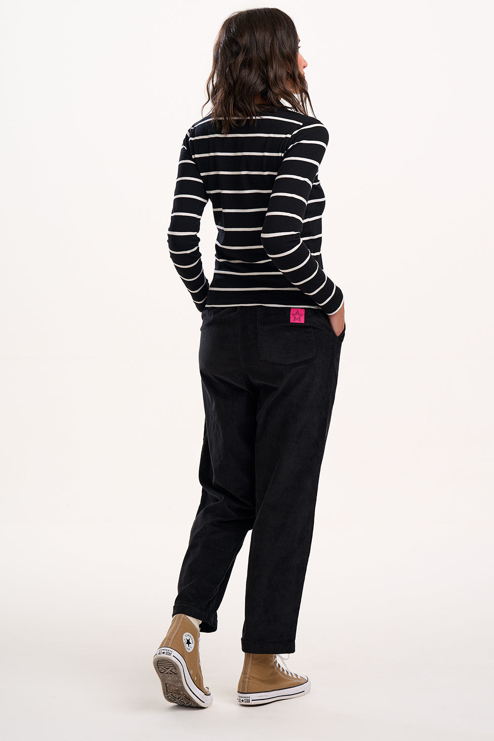 Person wearing a black and white striped shirt and black trousers on a white background
