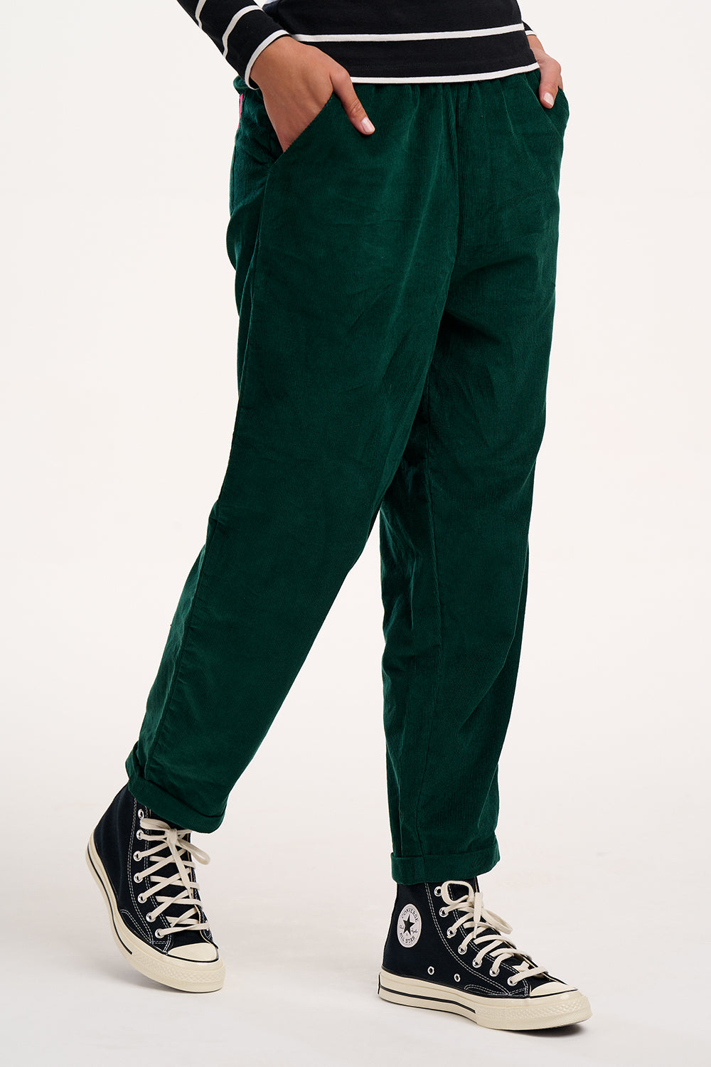 Green trousers worn by a person on a white background